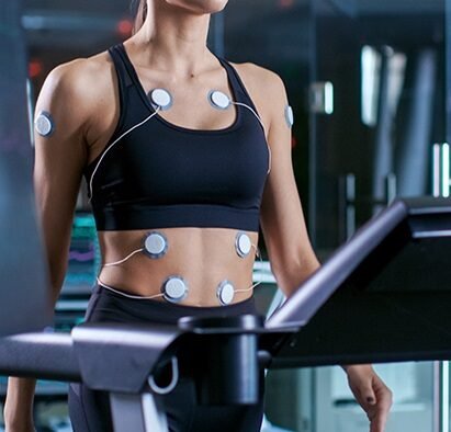 Female undergoing a TMT Test in Bhopal, attached to ECG electrodes while walking on a treadmill for cardiac stress testing.